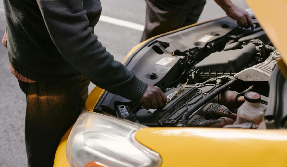 From above side view of crop anonymous ethnic male cab drivers revising modern vehicle bonnet on asphalt roadway — Photo by Tim Samuel on Pexels