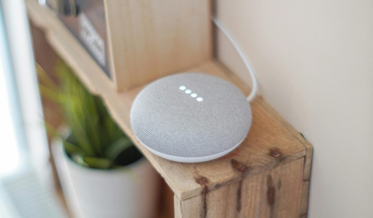 A Google Home Mini smart speaker on a wooden shelf, blending technology with home decor. — Photo by John Tekeridis on Pexels