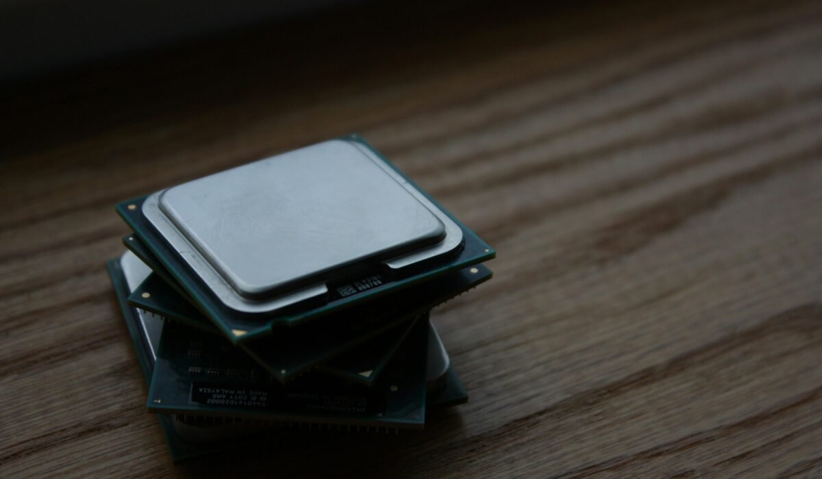Close-up of multiple computer CPUs stacked on a wooden surface, showcasing technology components. — Photo by Shawn Stutzman on Pexels