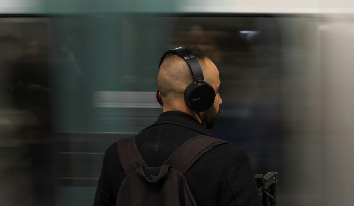 Man wearing headphones patiently waits for subway train indoors, creating a sense of motion and urban life. — Photo by ClickerHappy on Pexels
