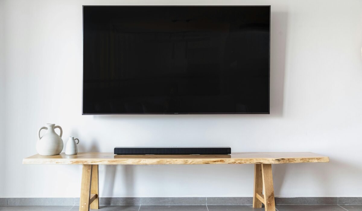 Stylish minimalist living room featuring a wall-mounted flat screen TV and wooden console. — Photo by yair elgazar on Pexels