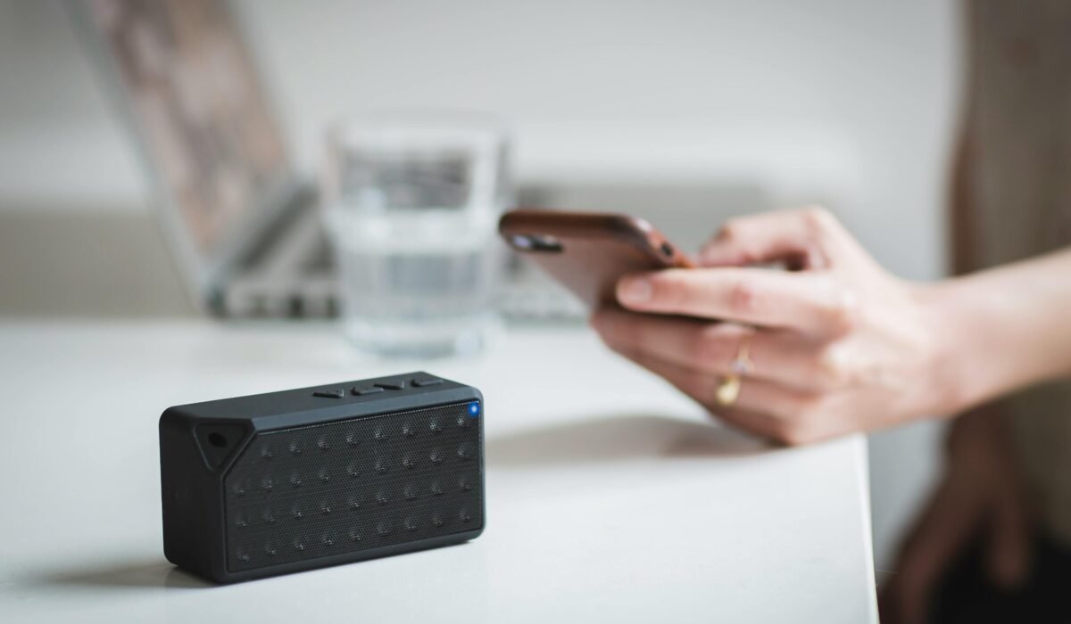 Person connecting a smartphone to a wireless speaker indoors, foreground focus. — Photo by Burst on Pexels