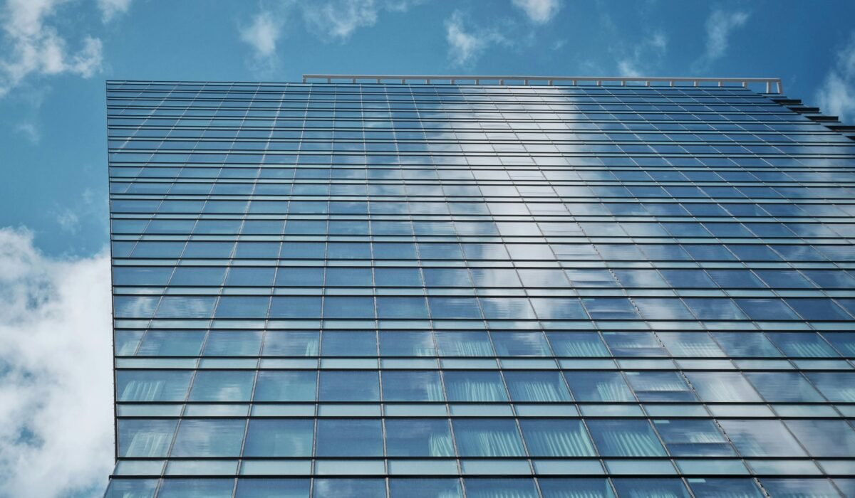Modern skyscraper with glass facade reflecting blue sky and clouds, showcasing urban architecture. — Photo by Thắng-Nhật Trần on Pexels