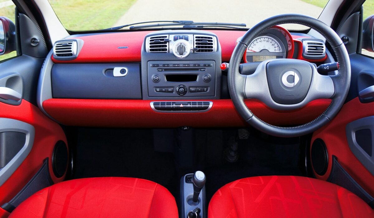 View of a compact car's red interior with a detailed dashboard and steering wheel. — Photo by Mike Bird on Pexels