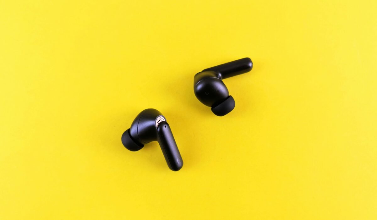 Minimalist black wireless earbuds on a bright yellow backdrop for tech and lifestyle themes. — Photo by Andrey Matveev on Pexels